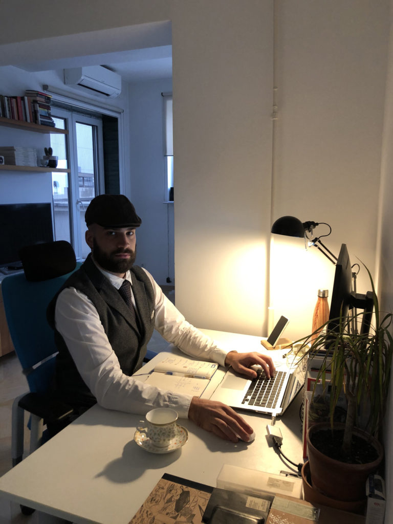 An image of a man sitting at a table under a dim light wearing tweed